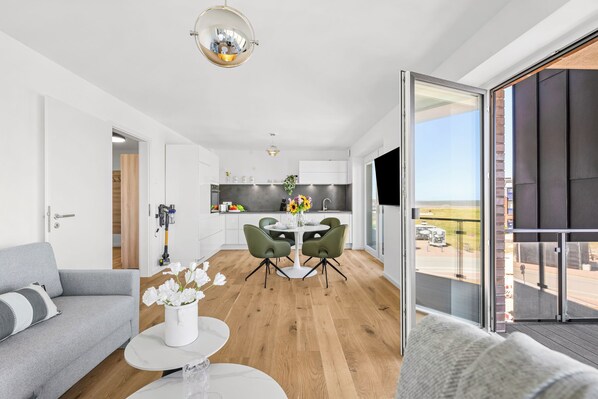 Un salon moderne comprenant un canapé, une table basse et un coin repas avec des chaises et une table.