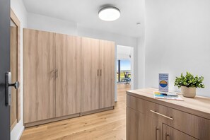 Ein modernes Hotelzimmer mit Holzboden, einem großen Kleiderschrank, einem Schreibtisch mit Blumentopf und Blick ins Freie.