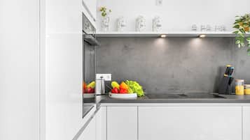 A modern kitchen with white cabinets, a grey backsplash, and a stainless steel range hood.