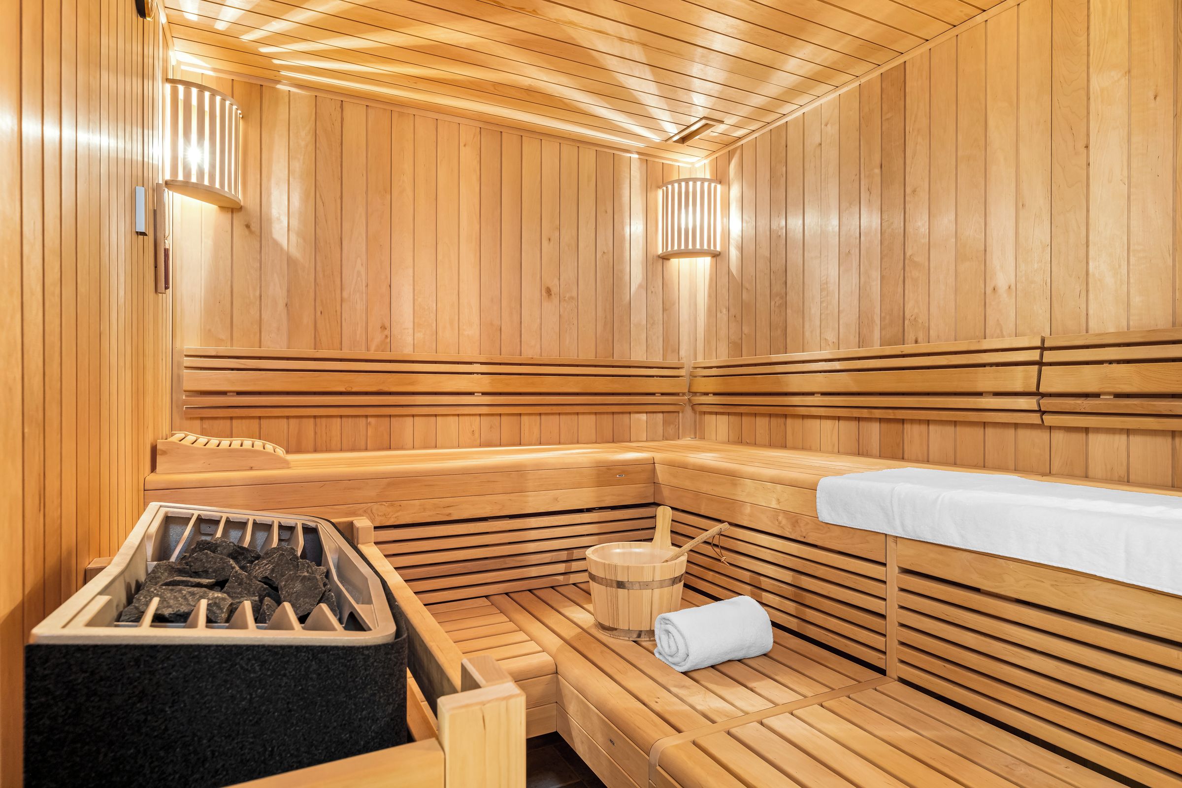 A sauna with wooden benches, a bench with a towel, and a bucket with a towel.