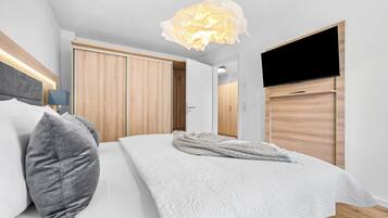 A modern bedroom with a bed, pillows, a TV, and a wardrobe.