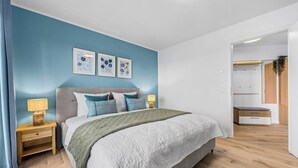 Ein Schlafzimmer mit einem Bett, Nachttischen, einer Lampe und einer Wand mit drei gerahmten Bildern.