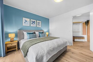 Ein Schlafzimmer mit einem Bett, Nachttischen, einer Lampe und einer Wand mit drei gerahmten Bildern.