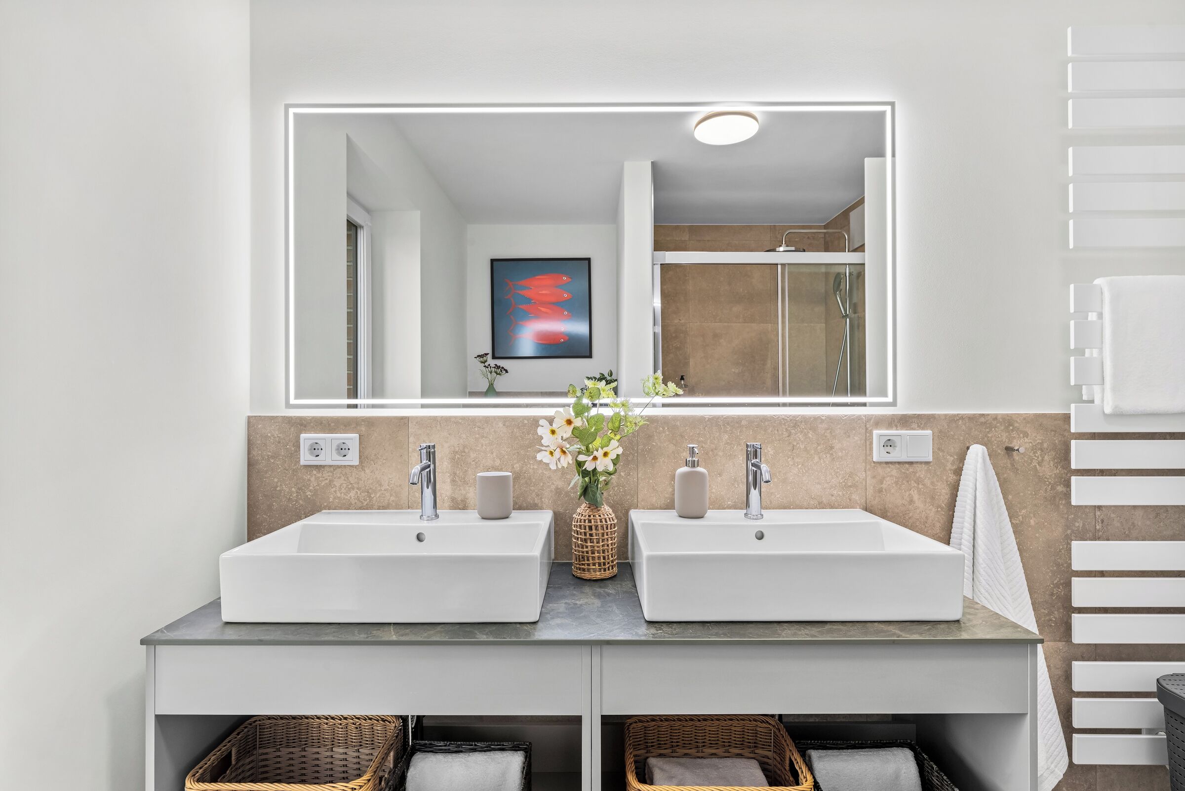 Ein modernes Badezimmer mit zwei Waschbecken, einem großen Spiegel und einer Dusche.