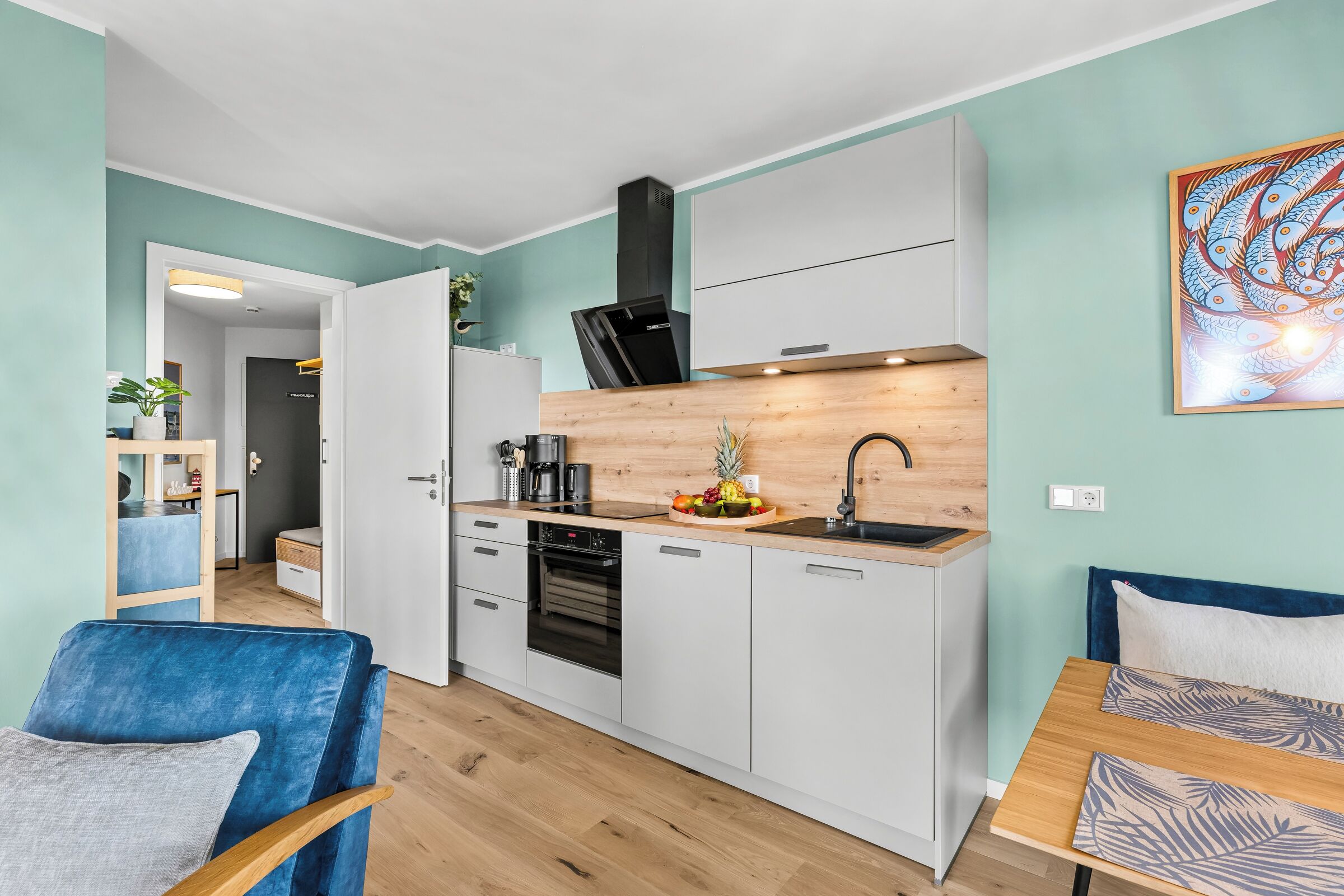 A modern kitchen with white cabinets, a black refrigerator, and a wooden countertop.