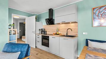 A modern kitchen with white cabinets, a black refrigerator, and a wooden countertop.