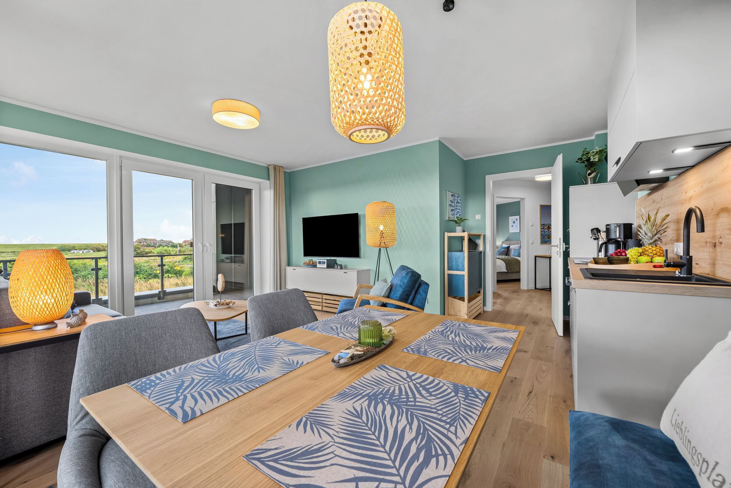 Een moderne leefruimte met een eethoek, keuken en een groot raam met uitzicht op de omgeving.