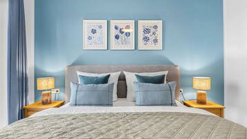 A bedroom with a bed, two bedside tables, a headboard, and three wall-mounted artworks.