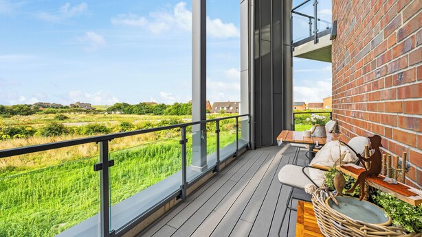 Ein Balkon mit Blick auf ein grünes Feld und Häuser in der Ferne.