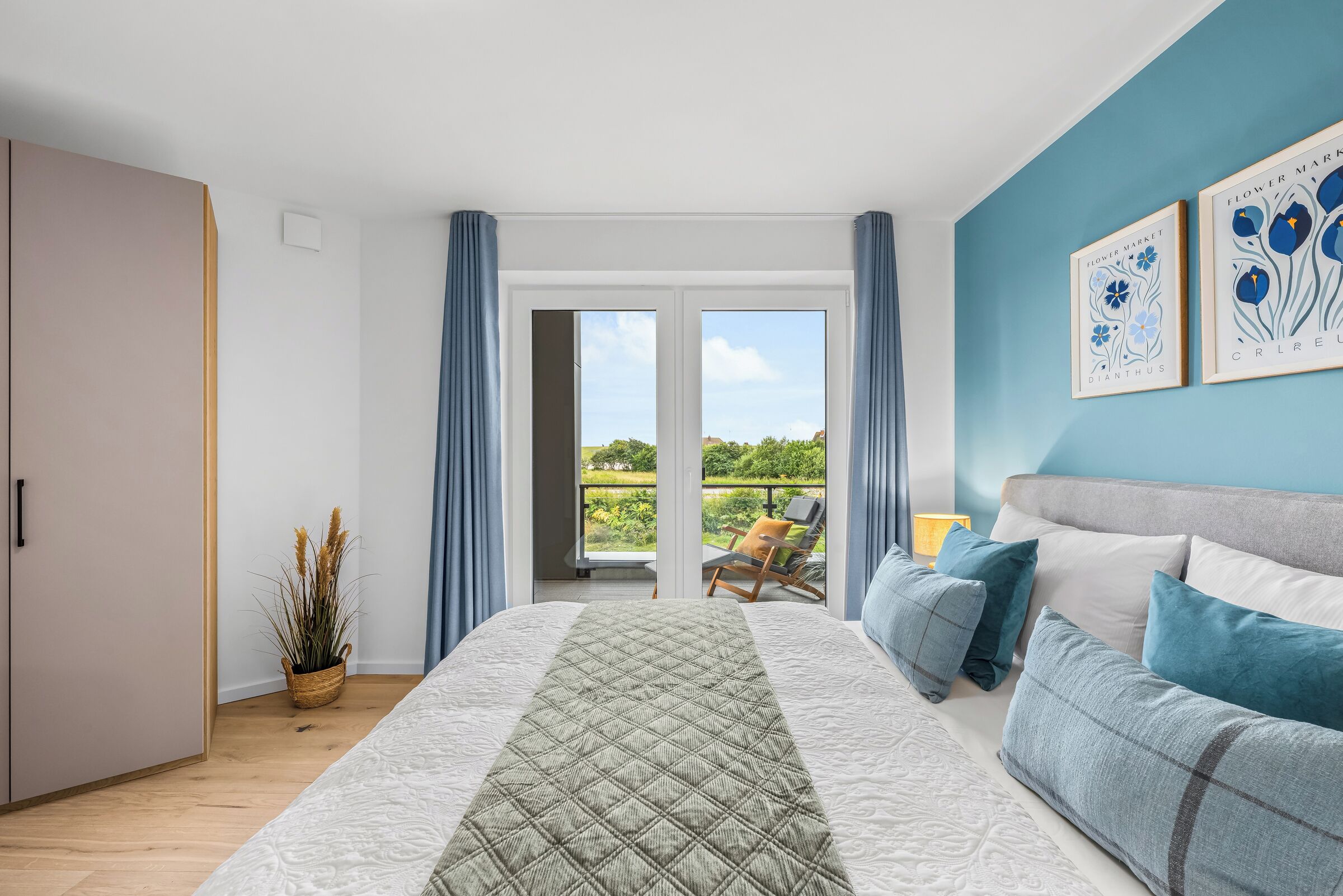 Ein Schlafzimmer mit Bett, einer Couch, Blick ins Freie und einer Tür.