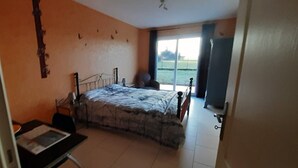 Un dormitorio con cama, una silla, un escritorio y vistas al exterior.