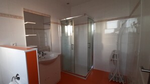 Un baño con cabina de ducha de vidrio, lavamanos y espejo.