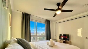 Ein Hotelzimmer mit Bett, Deckenventilator, Fernseher und Fenster mit Blick.