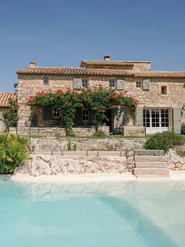A stone building with a pool in front.