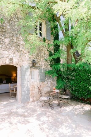 A stone building with a covered patio area featuring a table and chairs.