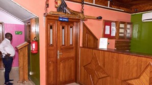 A reception area with a wooden reception desk, a fire extinguisher, and a sign indicating the location of the telephone. - hotel le printemps (Douala)
