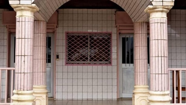 A hotel entrance with a sign reading "HOTEL Le Printemps," featuring a tiled facade, arched entrance, and decorative columns. - hotel le printemps (Douala)