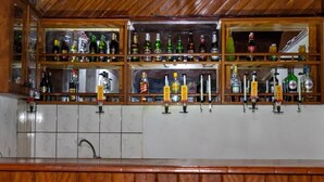 A bar area with multiple shelves of liquor bottles and a tiled backsplash. - hotel le printemps (Douala)