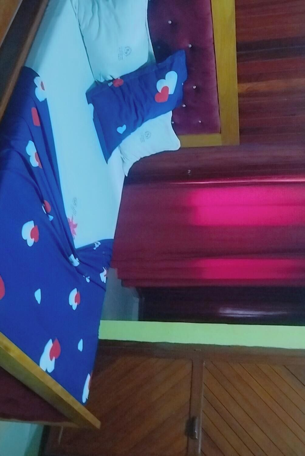 Una habitación con cama, armario de madera y mesita de noche.