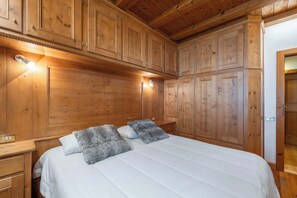A wooden-paneled bedroom with a large bed, two bedside tables, and built-in wardrobes. - Beautiful ground floor flat few steps from centre (Cortina d'Ampezzo)