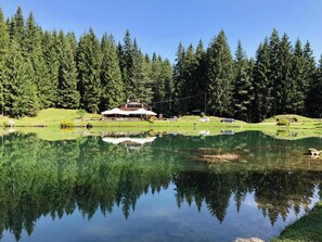 A lakeside lodge with a large building, surrounded by dense forest and a calm lake reflecting the scenery. - Beautiful ground floor flat few steps from centre (Cortina d'Ampezzo)