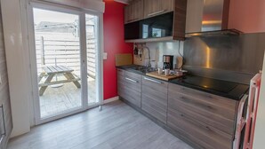 A kitchen with a sliding glass door leading to an outdoor area, a stainless steel range hood, and a wooden countertop. - Gite Brest at the End of the Pier – One of Fabie’s Gîtes (Brest)