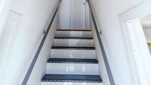 A modern staircase with glass railings, a wooden platform, and patterned steps. - Gite Brest at the End of the Pier – One of Fabie’s Gîtes (Brest)
