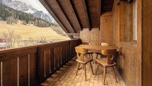 A wooden balcony with a table and chairs, overlooking a mountainous landscape. - Brand new apartment in San Vito di Cadore (San Vito di Cadore)