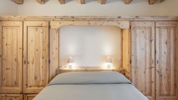 A bedroom with wooden paneling, a bed, and two bedside lamps. - Brand new apartment in San Vito di Cadore (San Vito di Cadore)