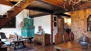 Un tavolo da pranzo in legno con una pentola di metallo, una scala in legno e un armadietto color petrolio in un ambiente accogliente.