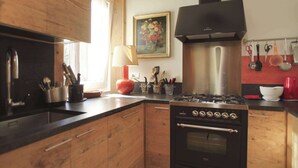 Una cocina con armarios de madera, estufa a gas y campana extractora de acero inoxidable.