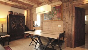 Un interior rústico de madera con una mesa de comedor, sillas y una lámpara colgante.