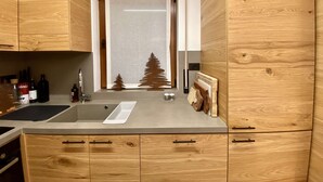 Une cuisine moderne avec des meubles en bois, un évier encastré et une fenêtre donnant sur les arbres.