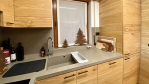 Une cuisine moderne avec des meubles en bois, un évier en acier inoxydable et une fenêtre donnant sur les arbres.