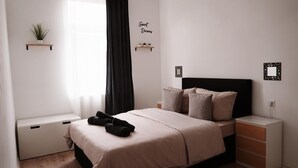 A neatly arranged bedroom with a bed, bedside tables, a window with curtains, and a wall-mounted shelf with a plant. - Vacation apartment - beautiful home Li-Apartments (Pforzheim)