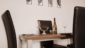A dining table set with a wine bottle, glasses, and a bowl of grapes. - Vacation apartment - beautiful home Li-Apartments (Pforzheim)