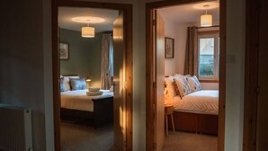 A hotel room with a bed, bedside table, and a window with curtains. - Royal Oak Court Retreat (Kirkwall)
