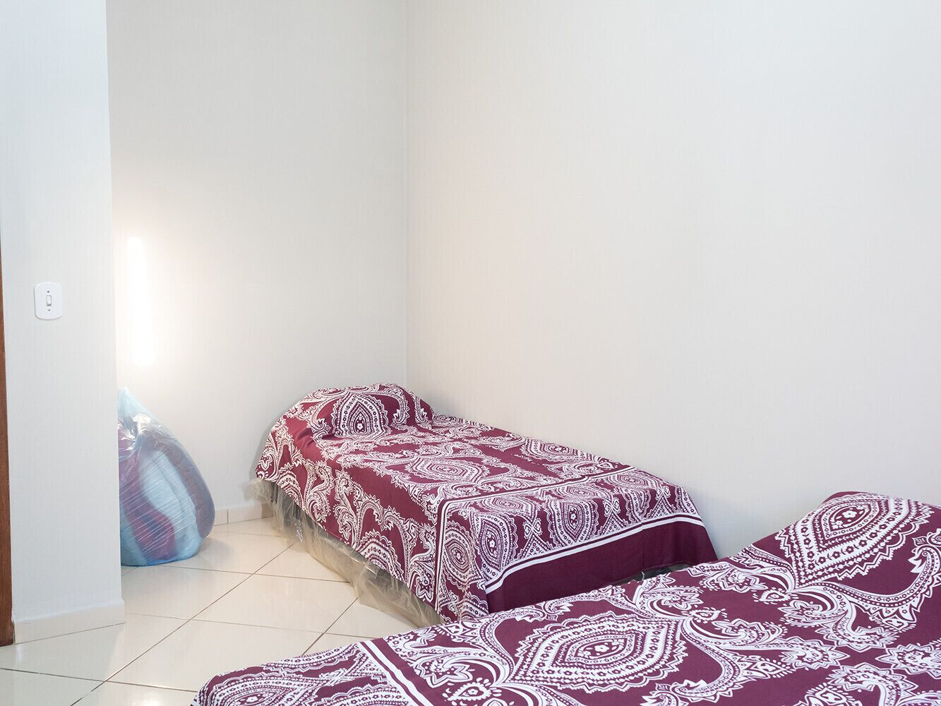 A small, clean room with two single beds, a blue bean bag chair, and a white wall.