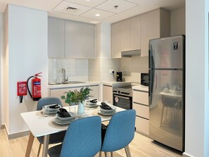 Une cuisine moderne avec un coin repas, des appareils en acier inoxydable et un extincteur.