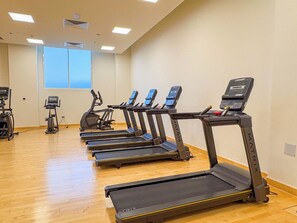 Une salle de sport équipée de plusieurs tapis de course et d’appareils d’exercice.