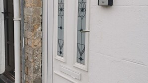 A white door with two glass panels, a stone wall, and a doorbell. - Roll-top bath, rain shower and space for 8 in the heart of Filey (North Yorkshire)
