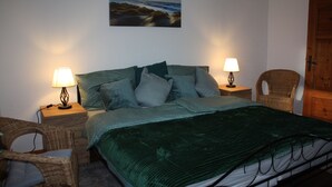 Une chambre bien rangée, avec un lit, deux tables de chevet, une chaise et une armoire en bois.