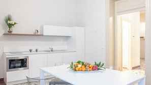 A modern kitchen with white cabinetry, a built-in oven, and a dining area with a table set for two.