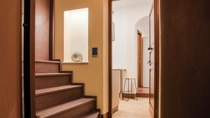 En trätrappa som leder upp till en liten plattform med en väggmonterad lampa och ett litet dekorativt snäckskal.