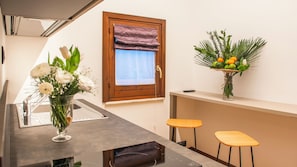 A kitchen with a window, a vase with flowers, and two stools.