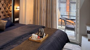 Ein Hotelzimmer mit Bett, Deckenventilator, Klimaanlage, einer Schiebetür und einem Balkon mit Stuhl.