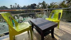 A balcony with a table and two chairs, surrounded by a railing with decorative elements. - SeaBreeze Nature Embrace Villa - Alibaug (Nagaon)