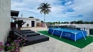 Una terraza en la azotea con piscina, escalones que conducen a una puerta y una palmera.