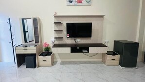 Una sala moderna con una televisión de pantalla plana montada en la pared, una consola de madera empotrada, un mueble pequeño y un altavoz negro.