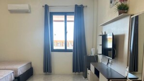 Una habitación de hotel moderna con una cama, un escritorio, un televisor y una ventana con cortinas.